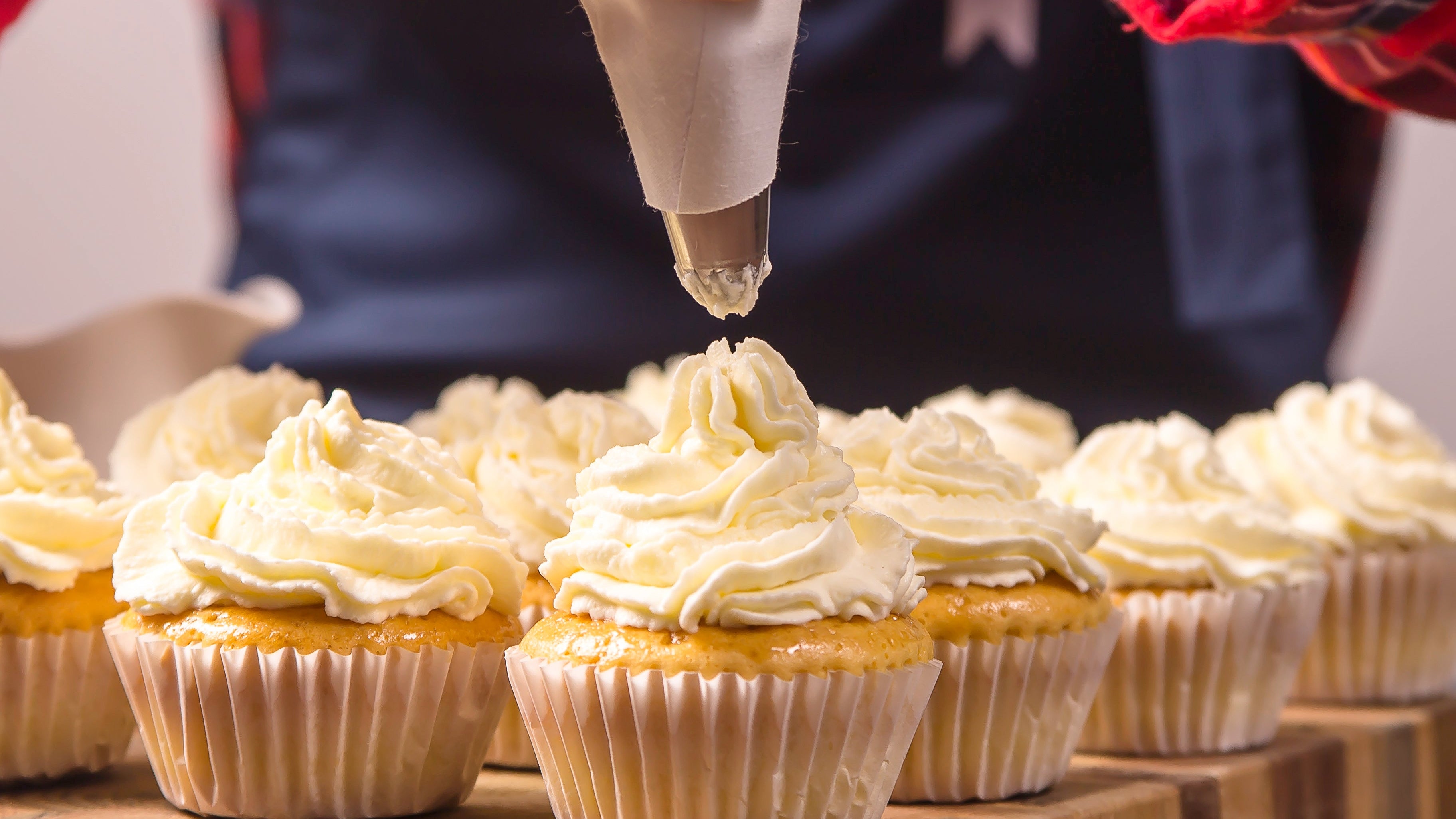 files/female-confectioner-blue-apron-plaid-red-shirt-applies-cream-cupcakes_1.jpg